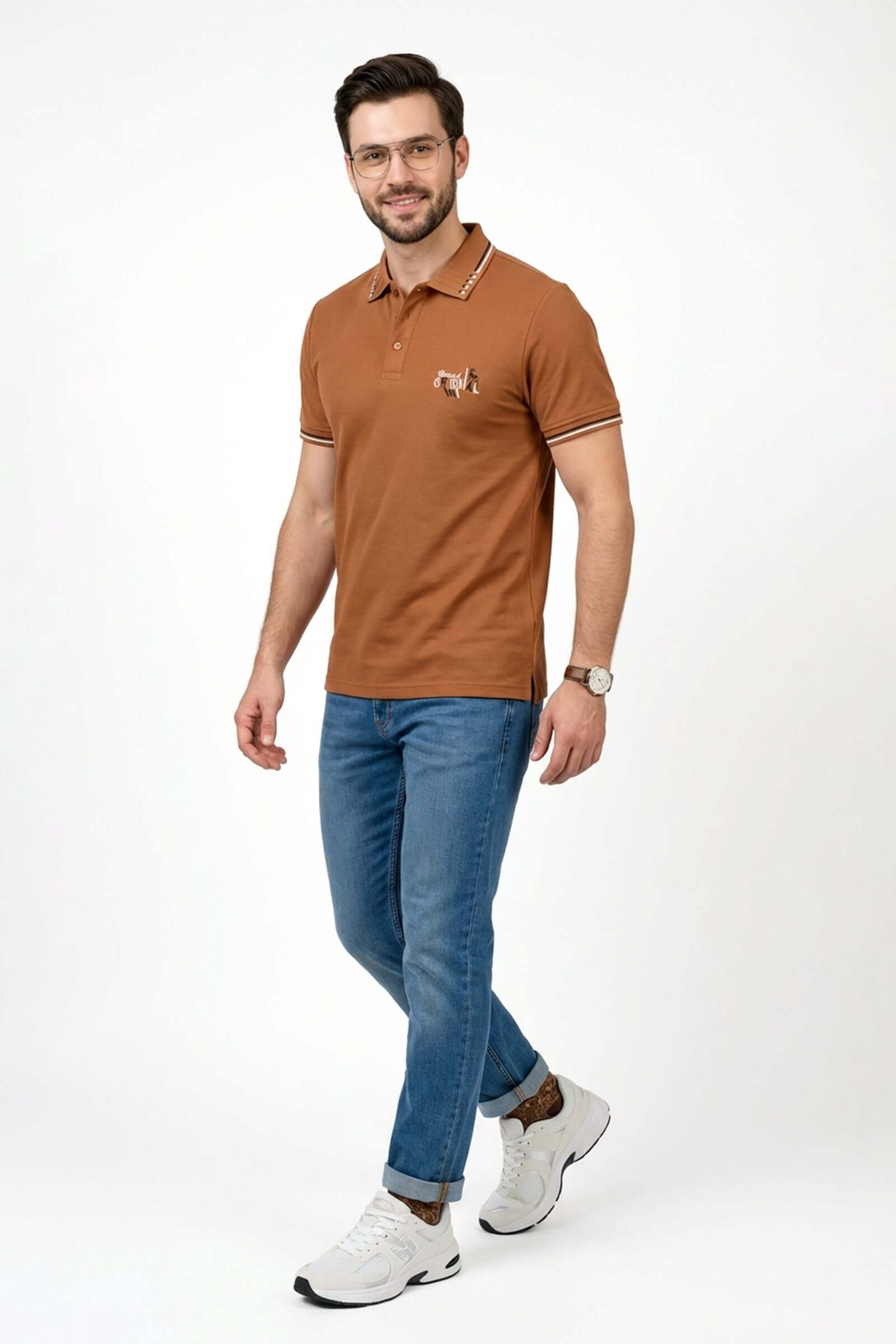 Hombre sonriente usando un polo de hombre de moda color marrón con detalles en un fondo blanco.