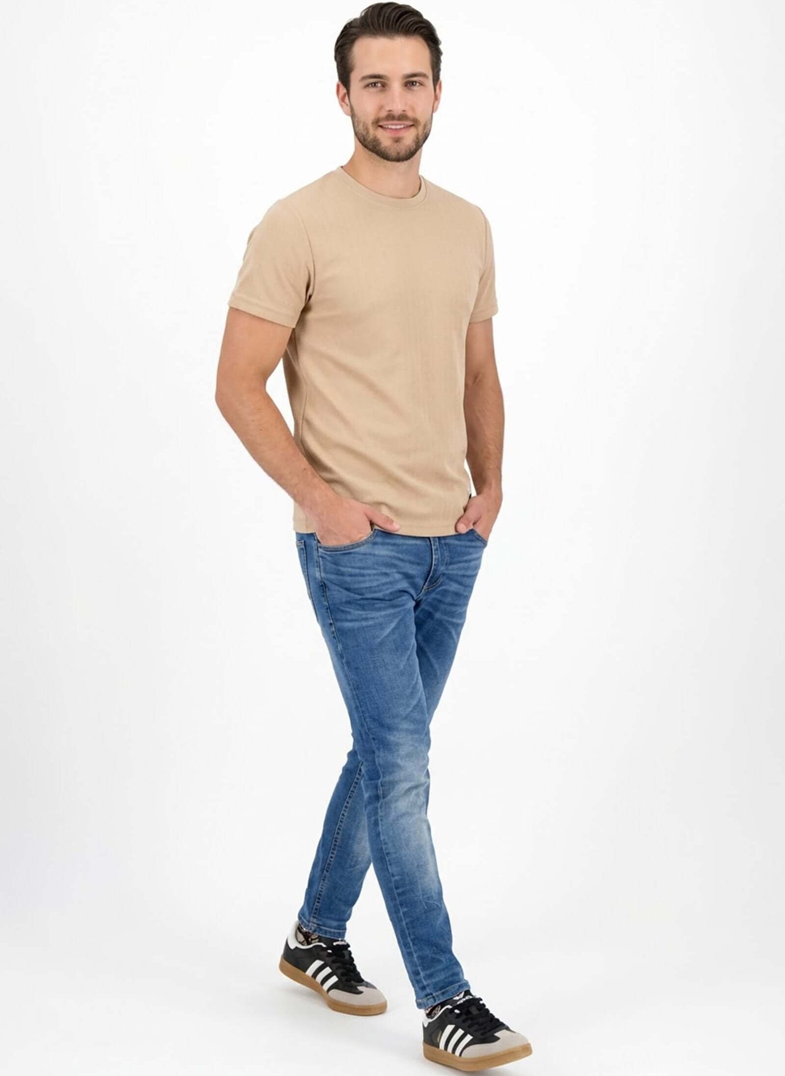 Modelo usando Jean de hombre casual y camiseta beige, luciendo un look moderno y relajado.