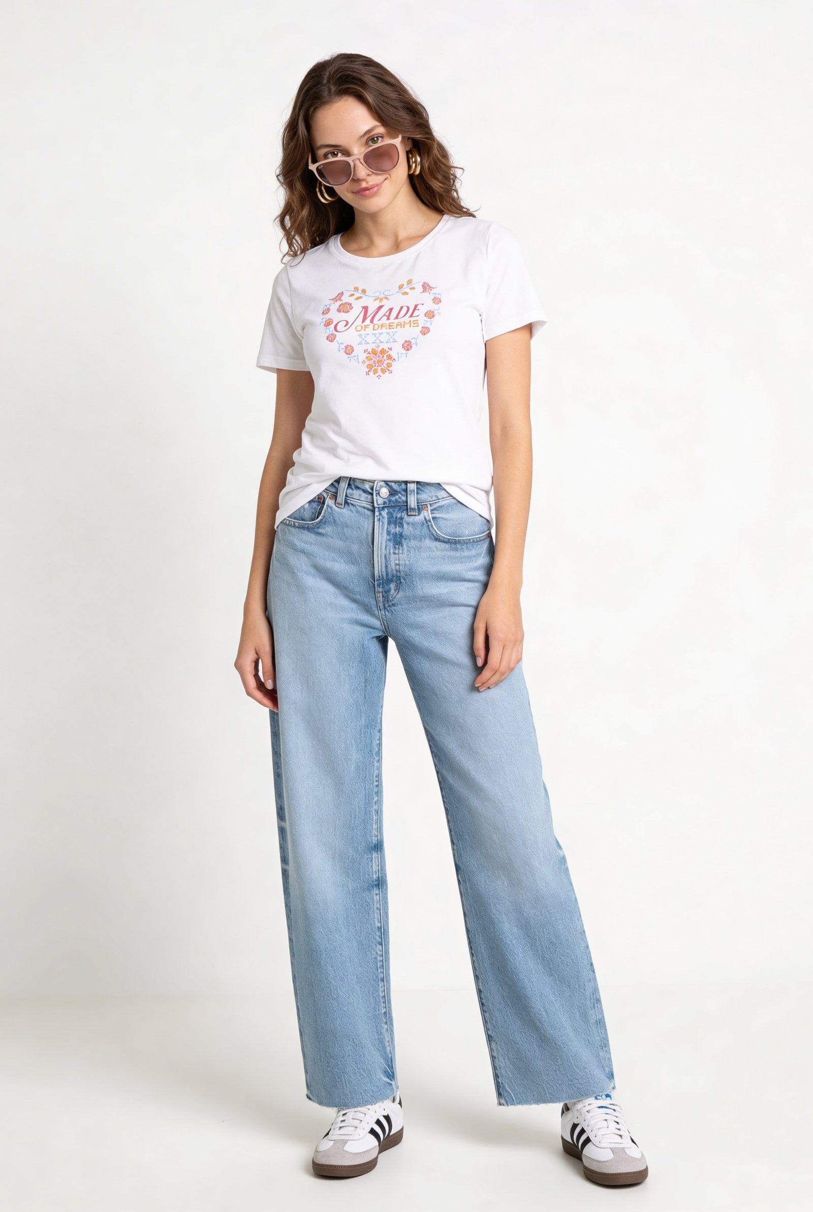 Camiseta de dama casual cuello redondo con diseño gráfico, modelo usando jeans claros y gafas de sol.