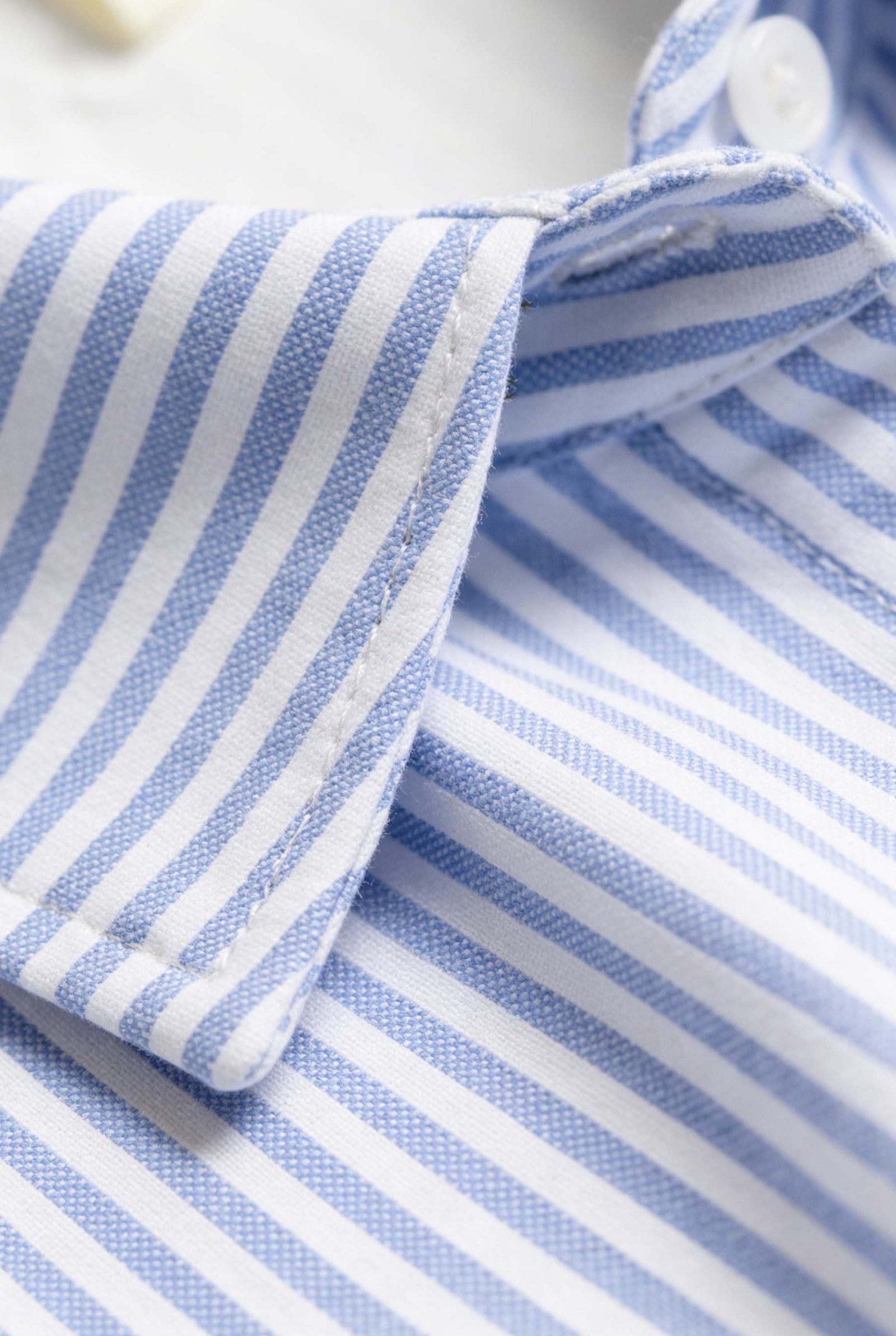 detalle de la tela de una camiseta de hombre con rayas azules y blancas, ideal para combinar con vestido camisero de dama.