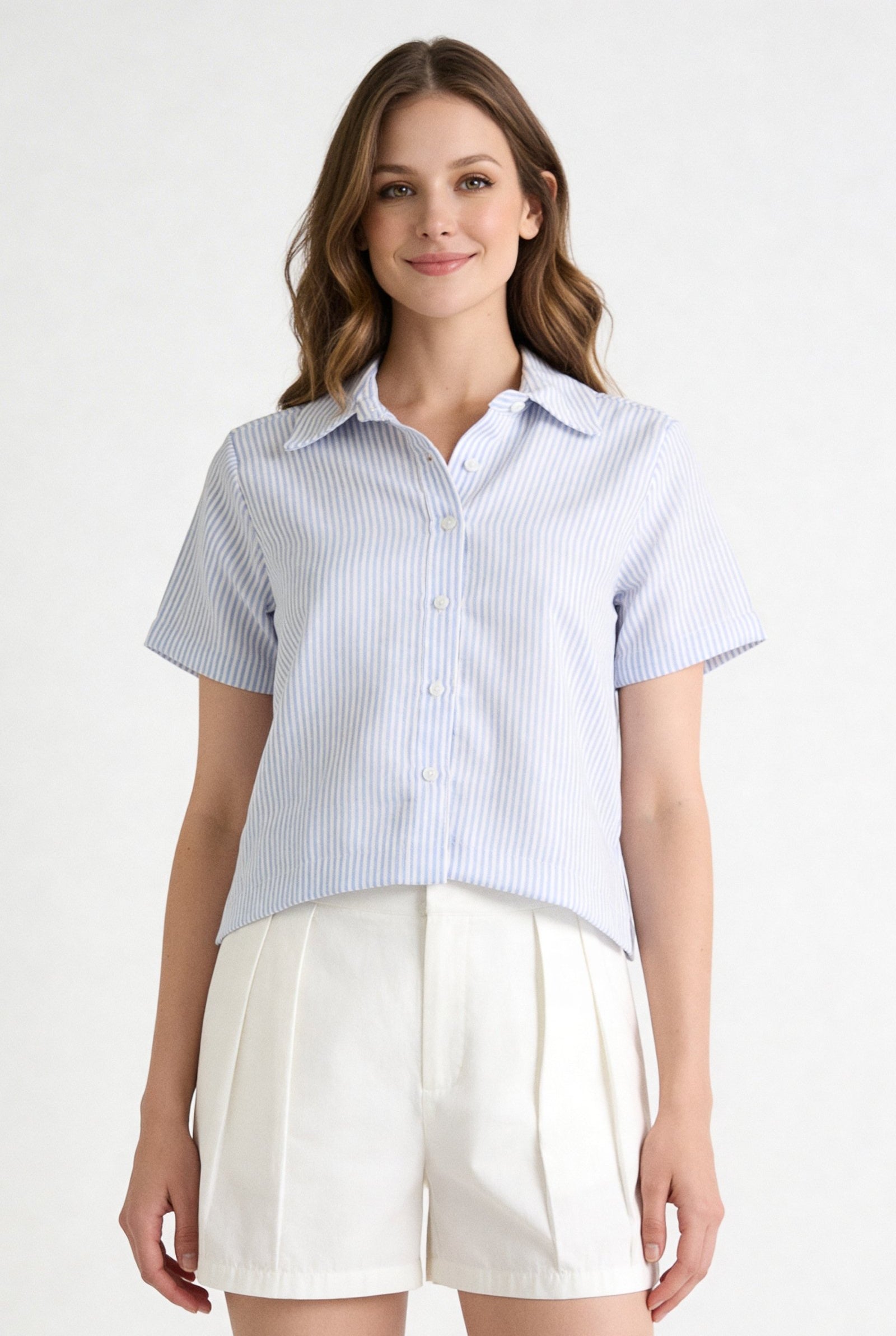 Blusa de dama moda manga corta en tonos claros, con botones y manga corta, combinada con pantalones cortos de verano.