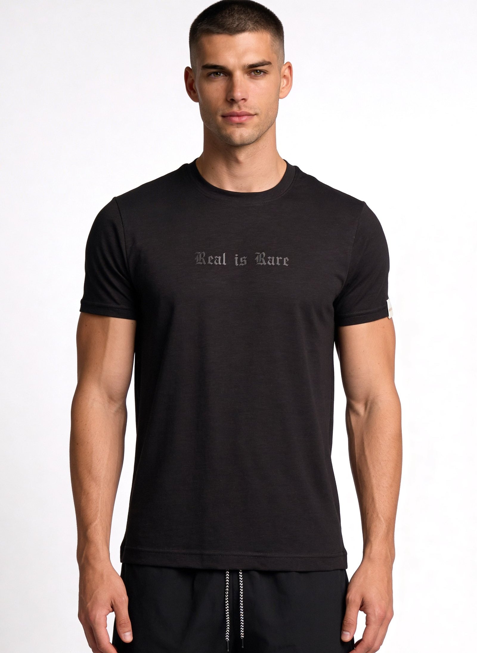 Camiseta de hombre sublimada en color negro con diseño 'Real is Rare' en el pecho.