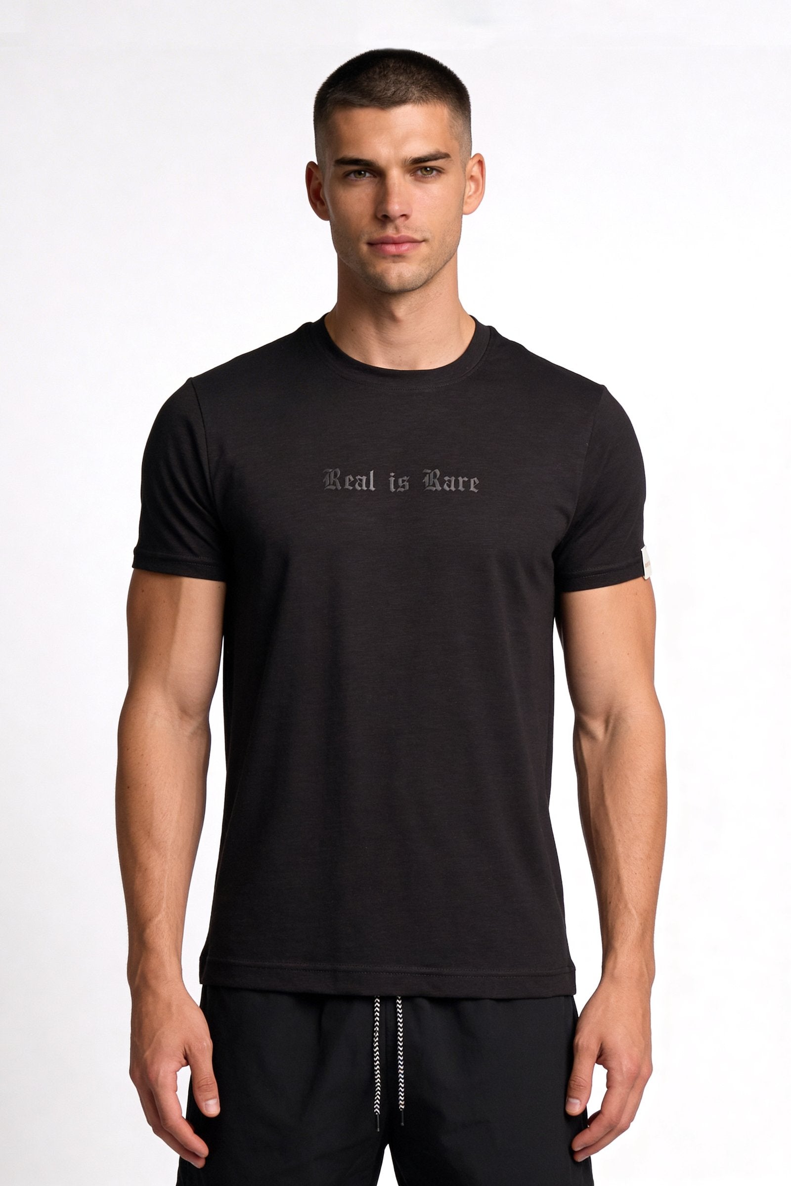 Camiseta de hombre sublimada en color negro con diseño 'Real is Rare' en el pecho.