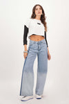 Joven modelo luciendo blusa semi ajustada y jeans anchos en un fondo blanco, perfecta para ocasiones casuales.