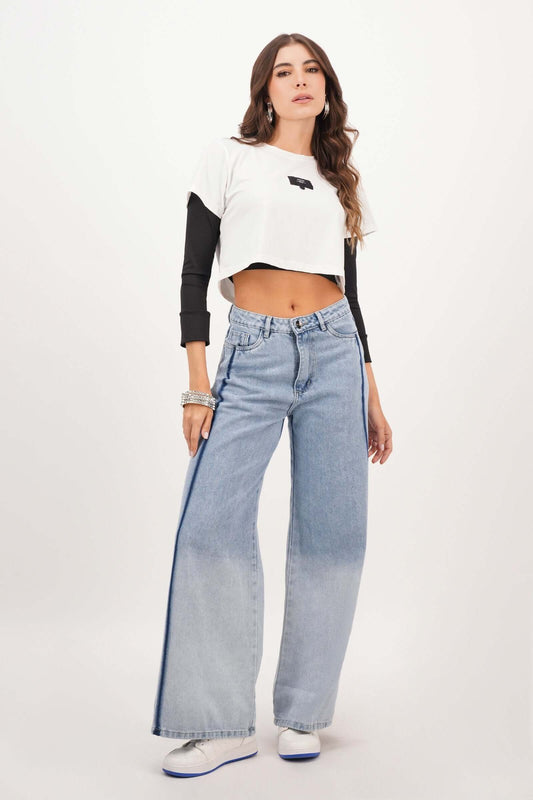 Joven modelo luciendo blusa semi ajustada y jeans anchos en un fondo blanco, perfecta para ocasiones casuales.