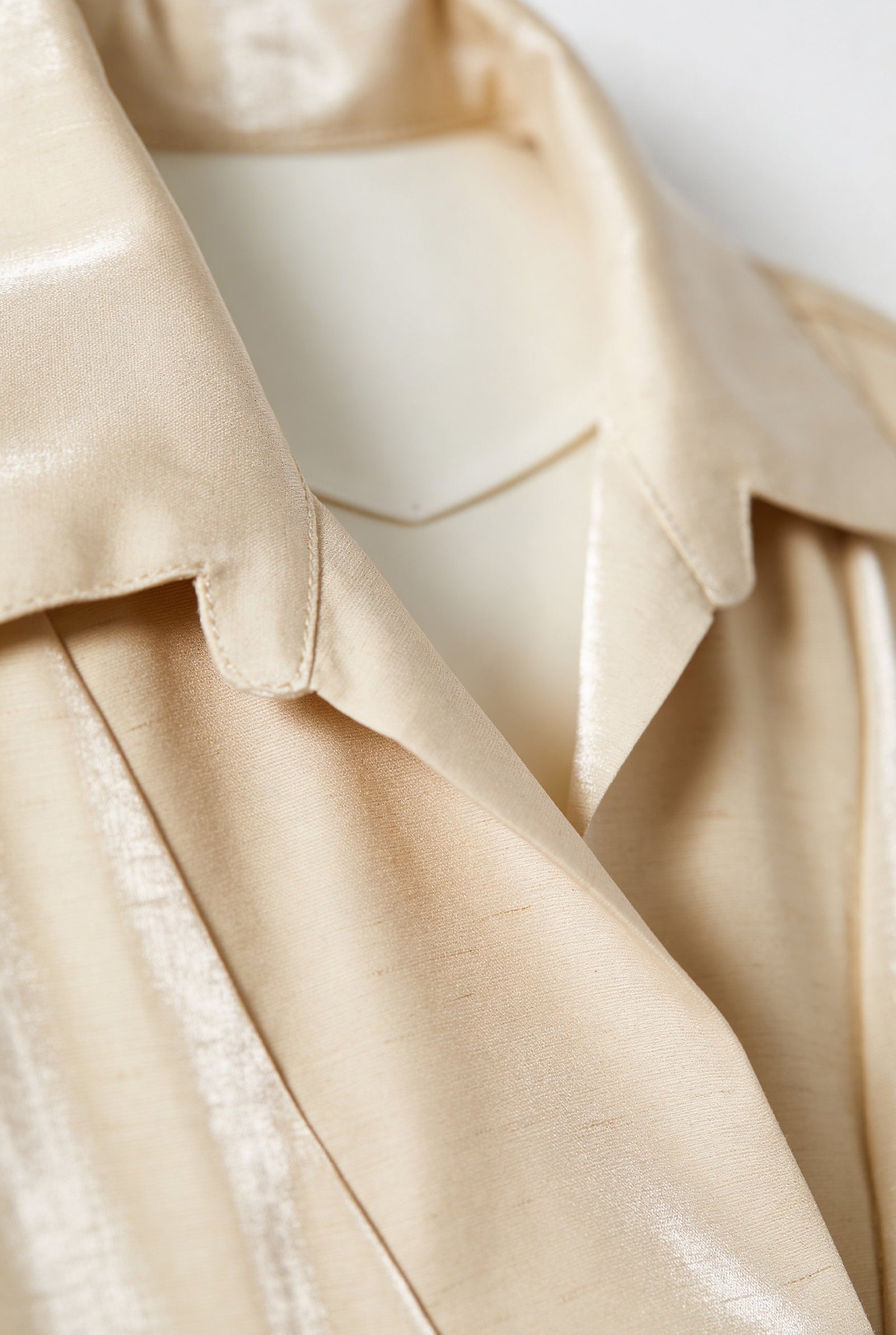 Blusa de dama moda en color crema con cuello elegante y textura brillante.