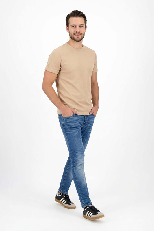 Modelo usando Jean de hombre casual y camiseta beige, luciendo un look moderno y relajado.