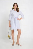 Vestido camisero de dama en color azul claro con cintilla y sandalias blancas.