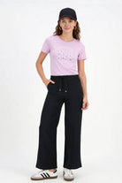 Camiseta de dama casual cuello redondo en color rosa, combinada con pantalones negros y gorra.