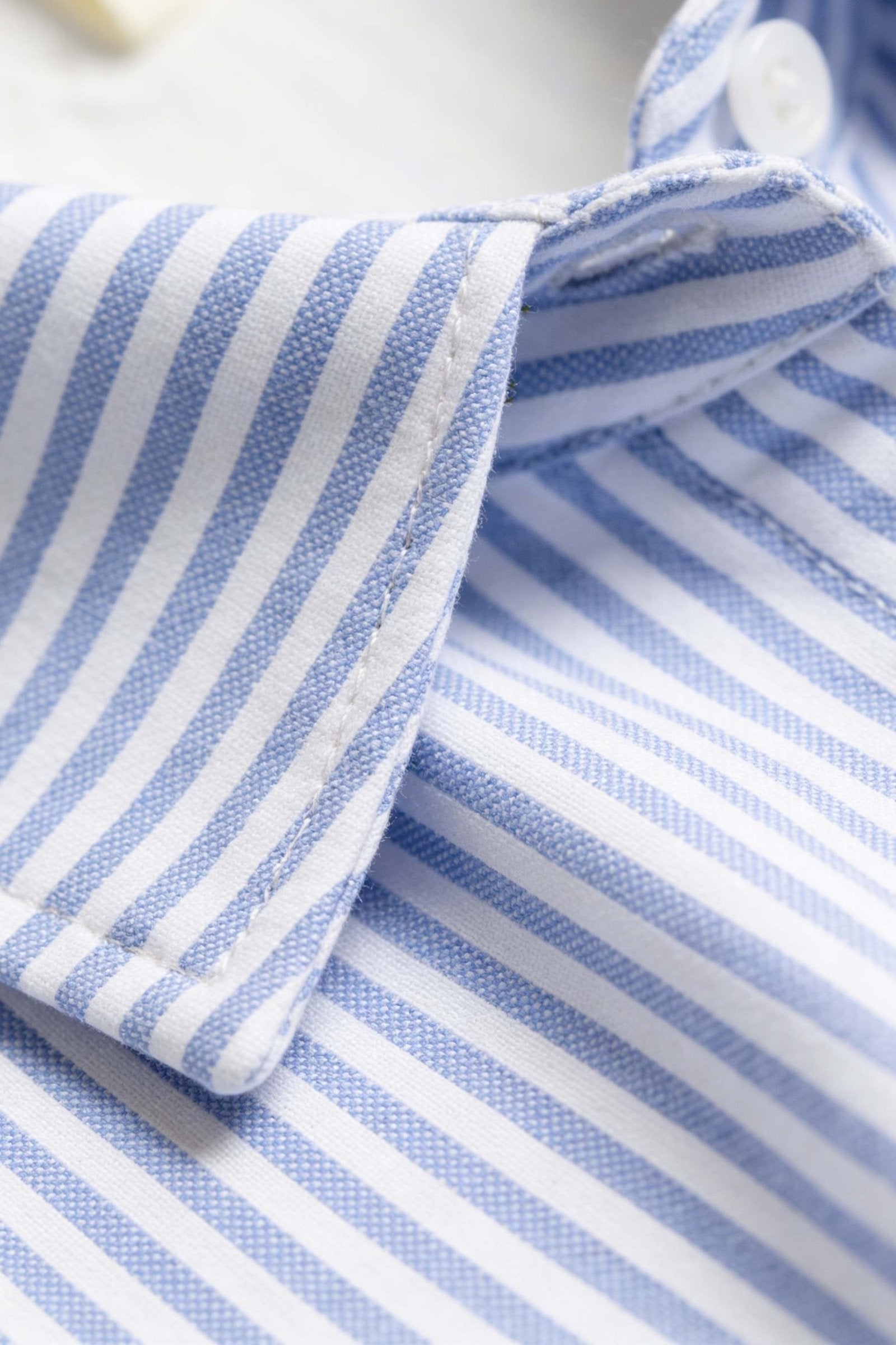 detalle de la tela de una camiseta de hombre con rayas azules y blancas, ideal para combinar con vestido camisero de dama.