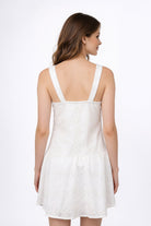 Vestido de dama de moda visto desde atrás, con tirantes anchos y falda corta en color blanco.