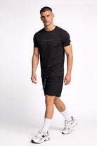 Camiseta de hombre sublimada en color negro, modelo masculino caminando con pantalones cortos deportivos.