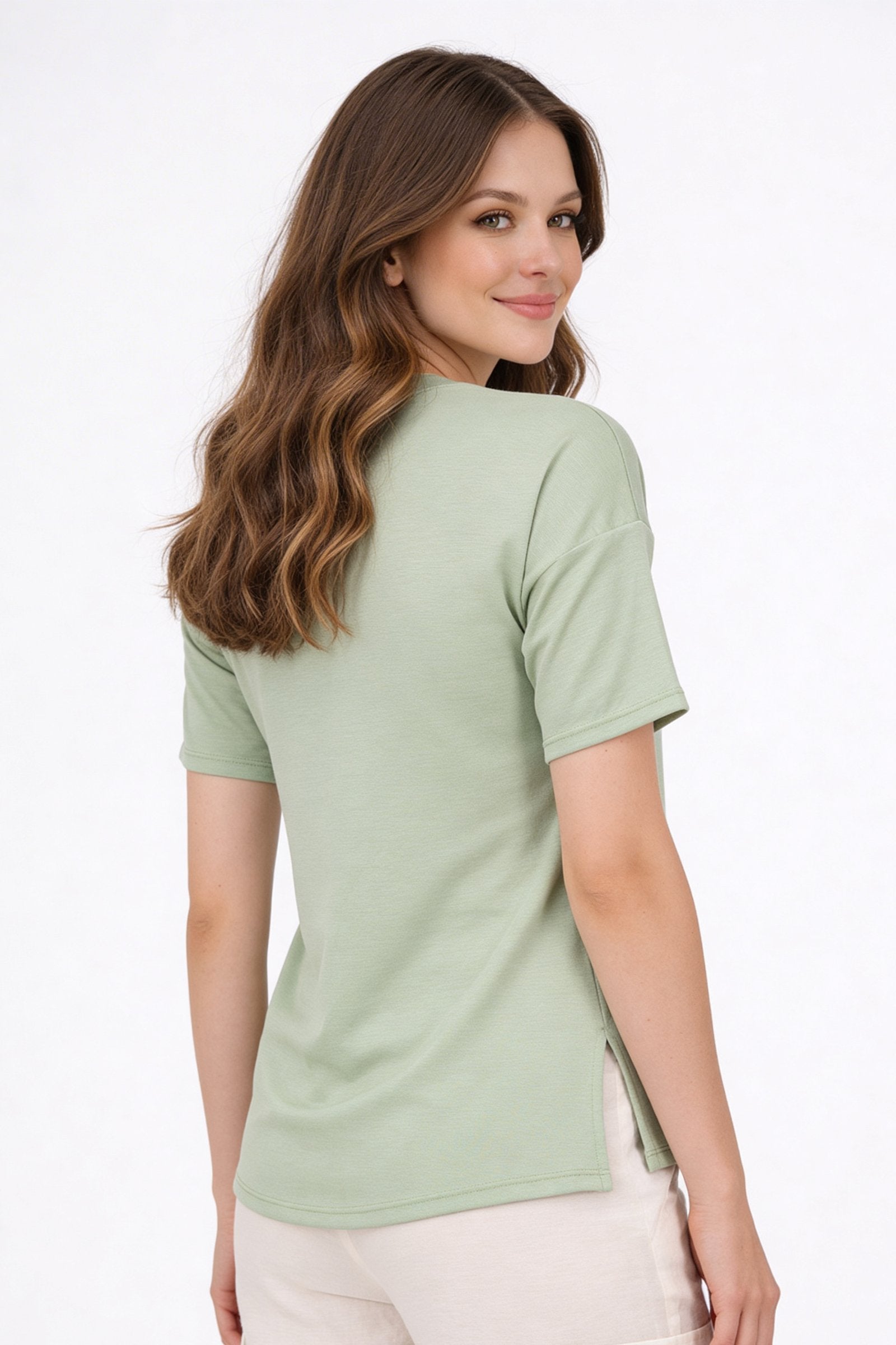 Mujer usando una blusa de dama casual color verde, vista desde atrás, con un diseño cómodo y moderno.