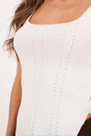 Blusa de dama básica ajustada en tejido blanco con detalles en relieve, ideal para un look casual y cómodo.