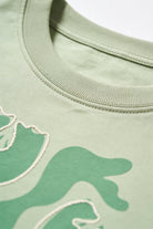 Blusa de dama casual en color verde claro, con detalles gráficos en la tela y un diseño moderno y relajado.